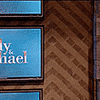 a close up of a wooden wall with a blue sign that says ' michael ' on it