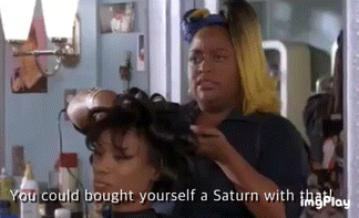 a woman is getting her hair done in a salon and talking about buying herself a saturn with that .
