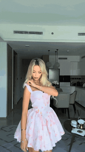 a woman in a pink floral dress is standing in a room