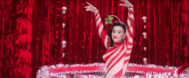 a woman in a candy cane outfit is dancing on a stage