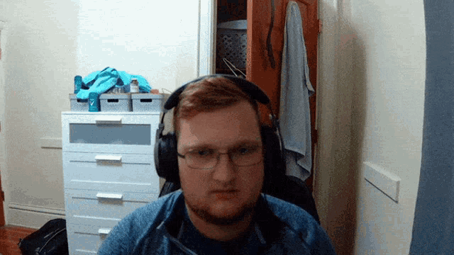a man wearing headphones and glasses is sitting in front of a white dresser