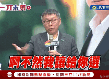 a man in a suit is talking into a microphone with chinese writing on the screen behind him