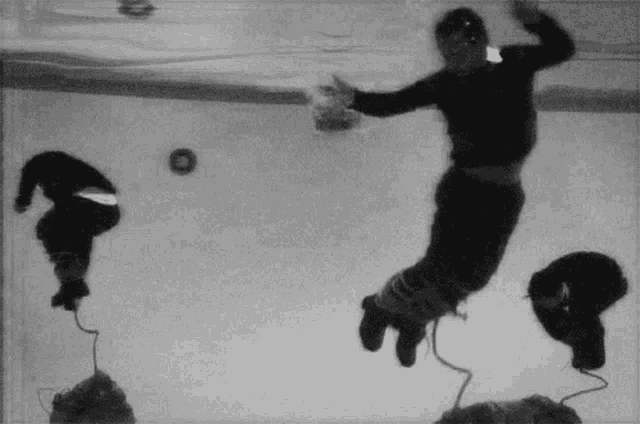 a black and white photo of a man jumping into a pool