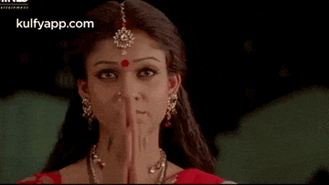 a woman in a red dress and jewelry is holding her hand up .