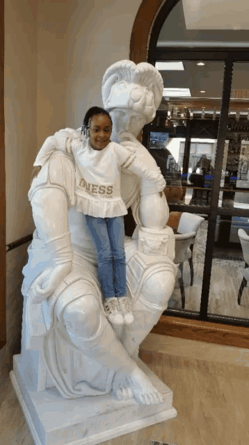 a little girl is posing with a statue wearing a dress