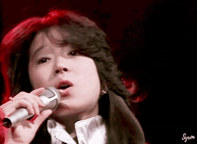 a woman is singing into a microphone with her mouth open
