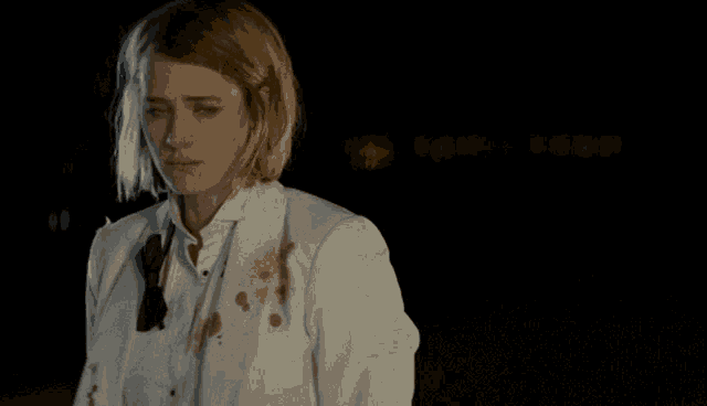 a woman in a white jacket with blood stains on it