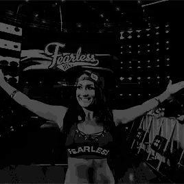 a black and white photo of a woman in a fearless top holding her arm in the air .