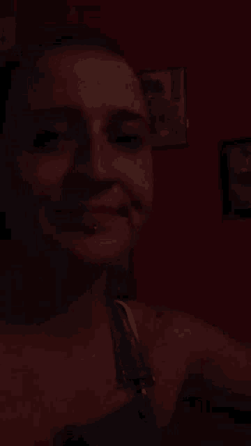 a woman taking a selfie in a dark room with a red wall behind her