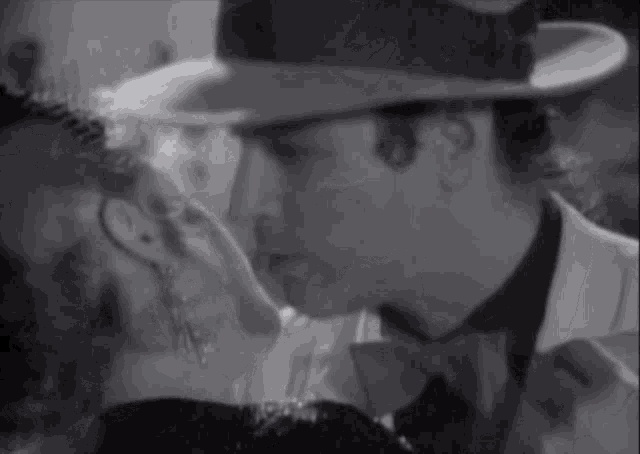 a man in a hat kisses a woman in a black and white photo