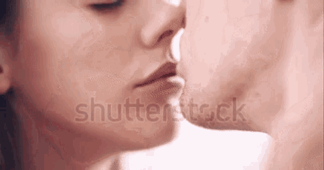 a man and a woman are kissing each other on the nose .