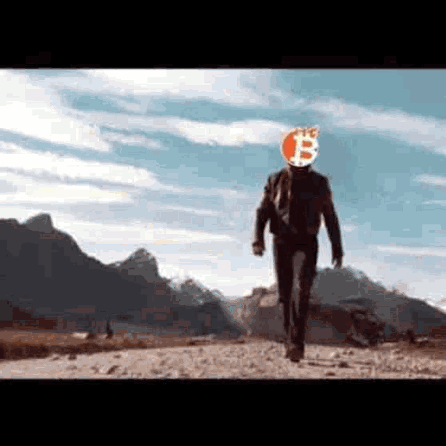 a man wearing a helmet with a bitcoin logo on his head is walking down a dirt road .