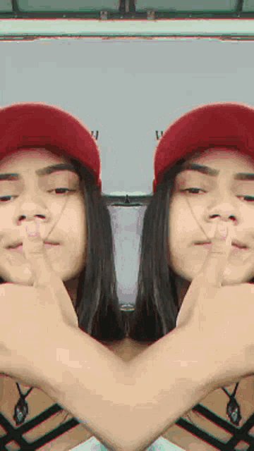 a girl wearing a red hat is making a heart shape with her hands