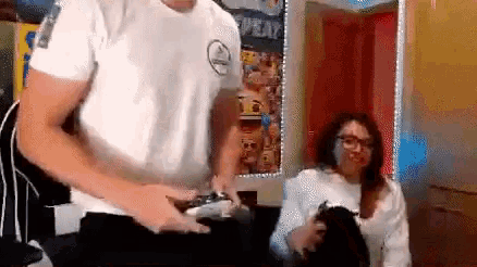 a man and a woman are playing a video game together . the man is holding a remote control .