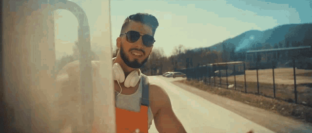 a man wearing headphones and sunglasses is standing on a road