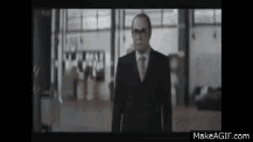 a man in a suit and tie is standing in a hallway in front of a window .