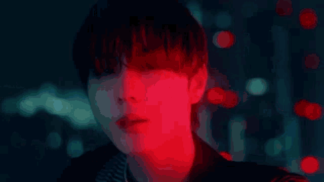 a close up of a person 's face with a red light behind him .