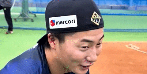 a man wearing a baseball cap with a mercari sticker on it is smiling .