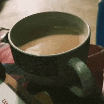 a cup of coffee sits on a table next to a piece of paper that says " exam "