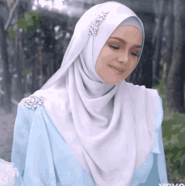a woman wearing a white hijab and a blue dress with yoyo written on the bottom