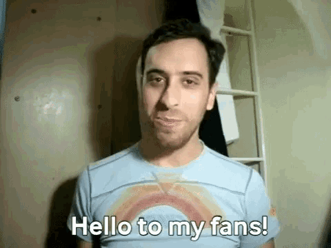 a man in a rainbow shirt is saying hello to his fans