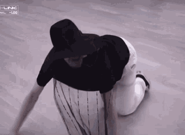 a person wearing a black shirt and white pants is crawling on the floor .