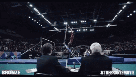 a gymnast is doing a trick on a parallel bars in front of a crowd