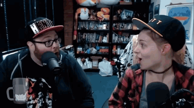 a man and a woman are talking in front of a microphone with the man wearing a hat that says henry