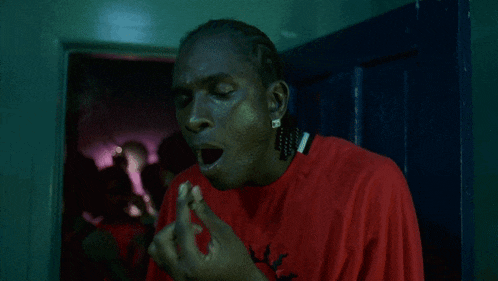 a man in a red shirt is smoking a cigarette