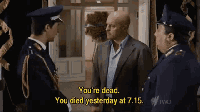 a man in a suit is talking to two police officers and says " you 're dead you died yesterday at 7:15 "