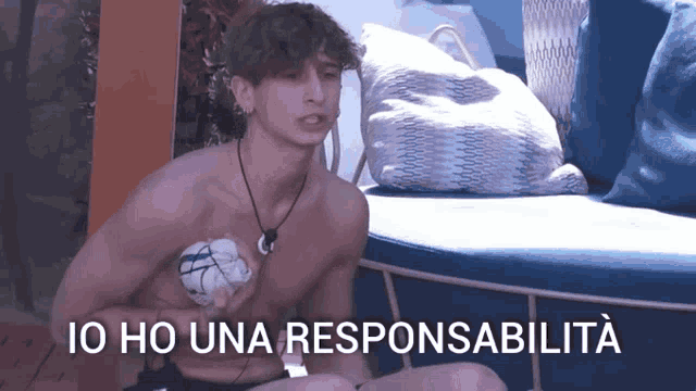 a shirtless man sits on a couch with the words io ho una responsabilita written on the bottom
