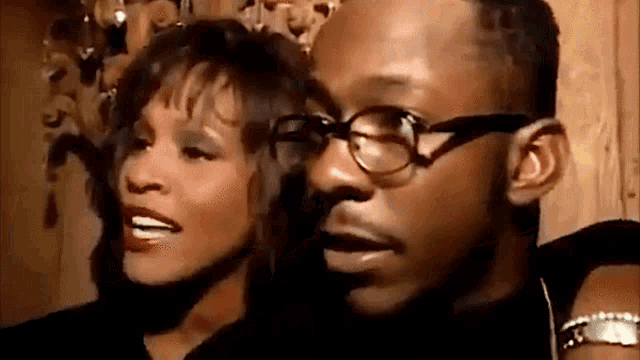 a man and a woman are standing next to each other and smiling . the woman is wearing glasses .