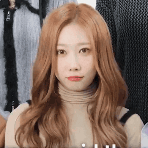 a woman with long red hair is wearing a turtleneck sweater .