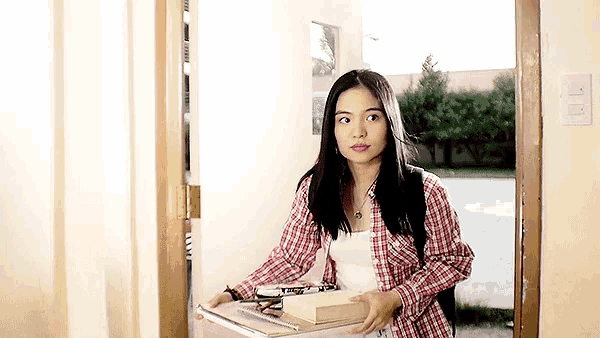 a woman in a plaid shirt is carrying books