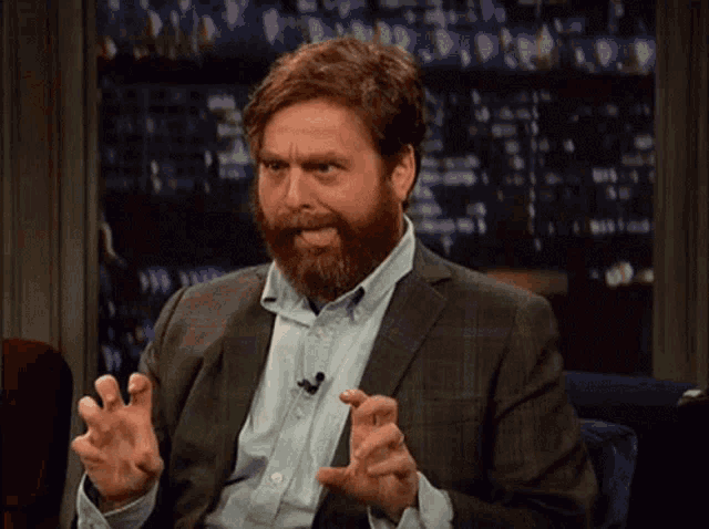 a man with a beard is sticking his tongue out while wearing a suit