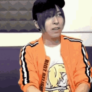 a person wearing an orange jacket with riot religion written on it