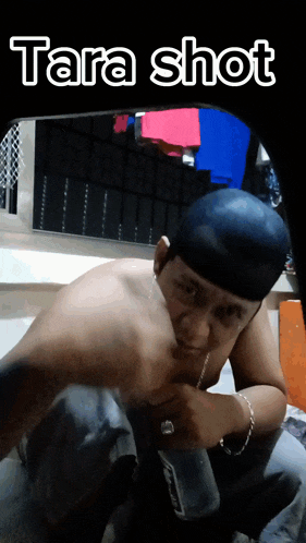 a man without a shirt is kneeling down with tara shot above him