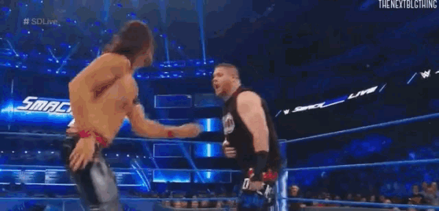 a wrestler is standing in a wrestling ring while a referee watches .