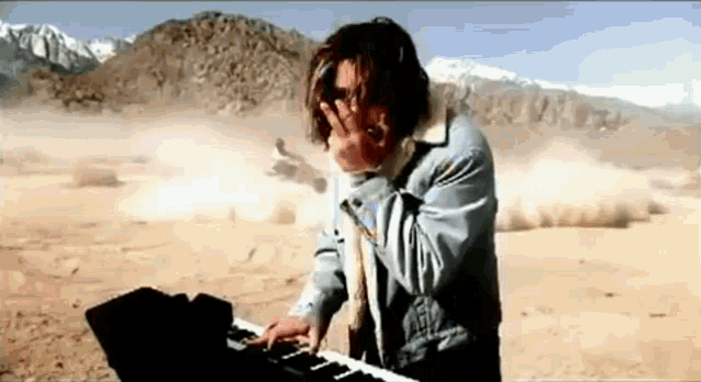 a man is playing a piano in the desert .