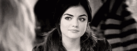 a black and white photo of a woman looking at the camera with a striped shirt in the background .