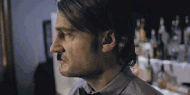 a man wearing a bow tie looks to the side