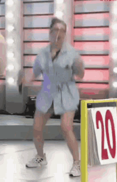 a woman is dancing on a stage in front of a sign that says 20 .