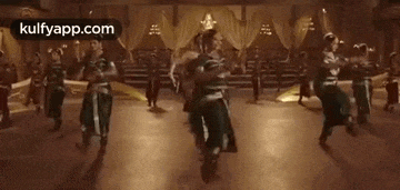 a group of people are dancing in a room in a movie .