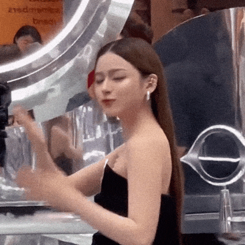 a woman in a black strapless dress stands in front of a nissan sign