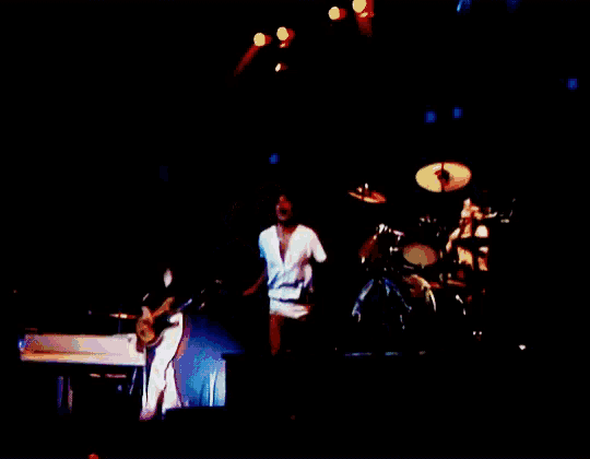 a man in a white shirt is singing on a stage