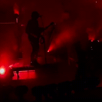 a silhouette of a man playing a guitar in front of a microphone