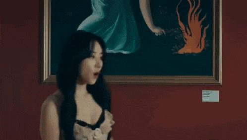 a woman in a very revealing dress is standing in front of a painting .