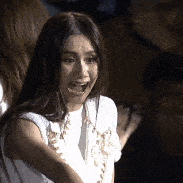 a woman with a surprised look on her face wearing a white top