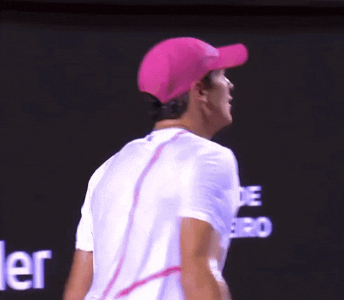 a man wearing a pink hat and a white shirt stands in front of a screen that says ' ler ' on it