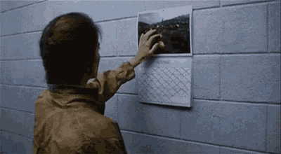 a man is pointing at a picture on a calendar on a brick wall .